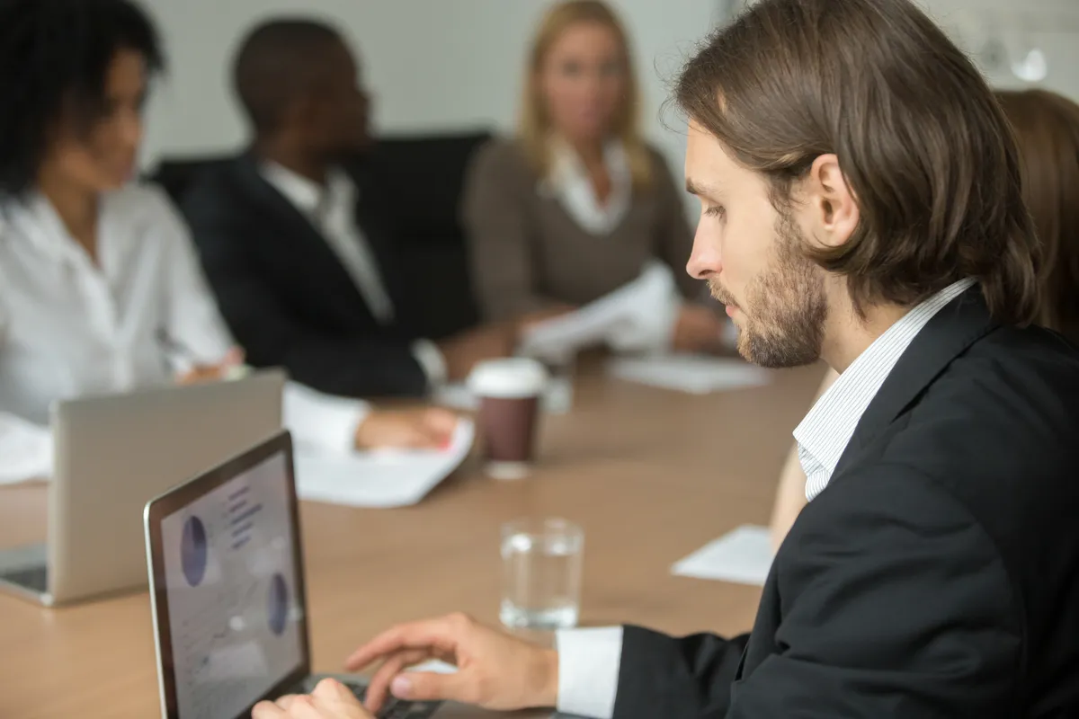A professional working on a laptop during a meeting.
