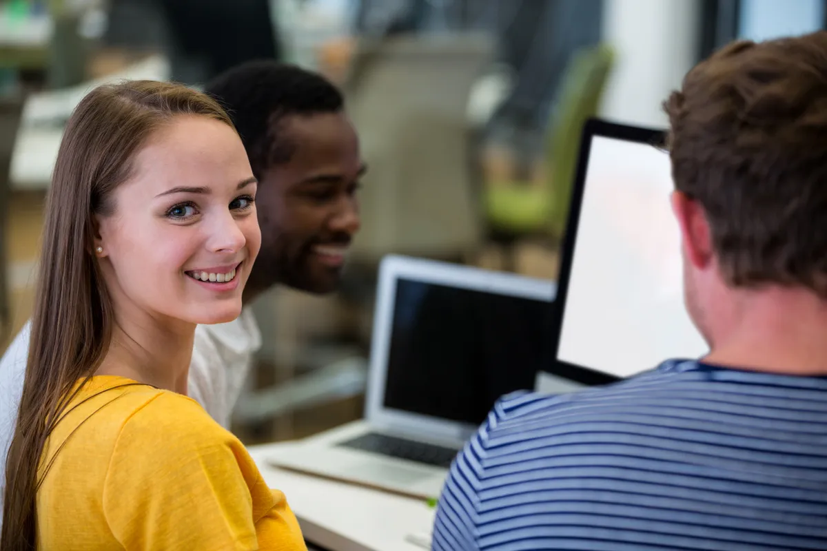 A smiling young professional working with colleagues in a bright office.