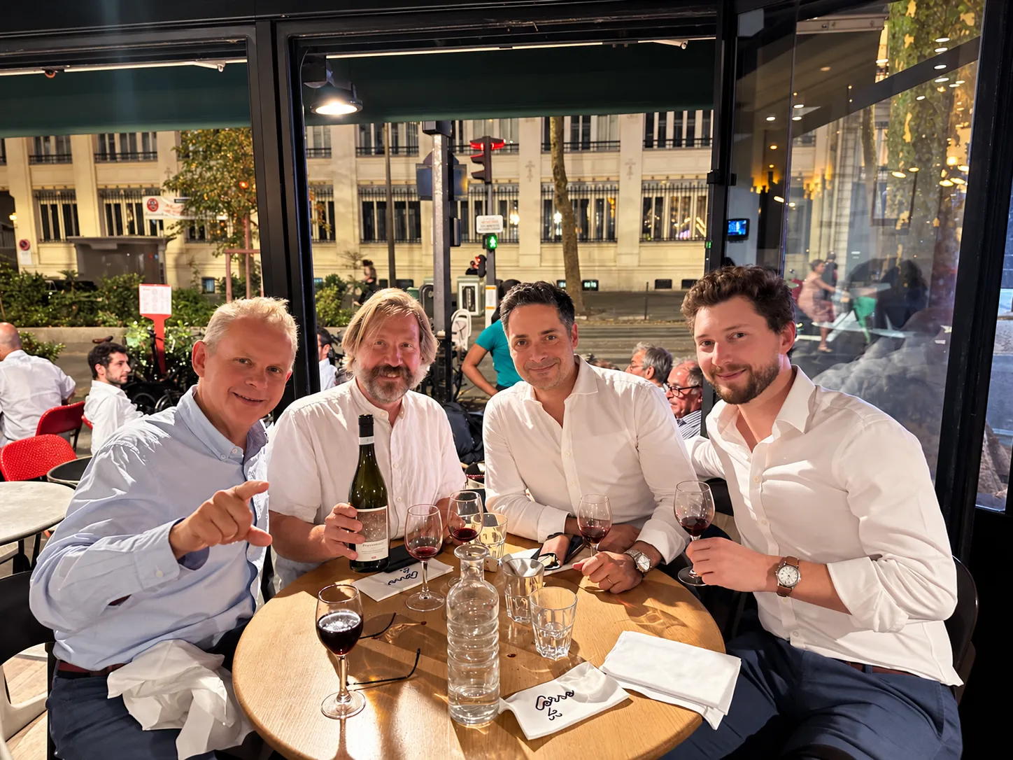 Four smiling professionals around a table at dinner.